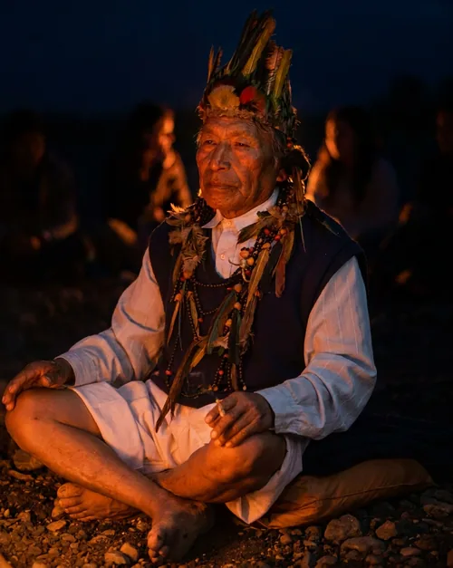 El Taita Aurelio Guamán sentado de noche junto al fuego durante un trabajo espiritual en Ecuador